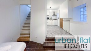 A modern apartment with a staircase leading to a kitchen, a small balcony, and a tiled floor.