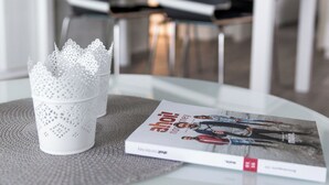 A modern dining area with a white table, two chairs, and a decorative white object on the table. - // HOUSE DEICHBLICK - APARTMENT 1 // (Norderney)