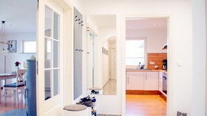 A modern kitchen with white cabinets, a wooden countertop, and a coffee machine.