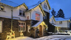 A snow-covered street with houses adorned with holiday lights.