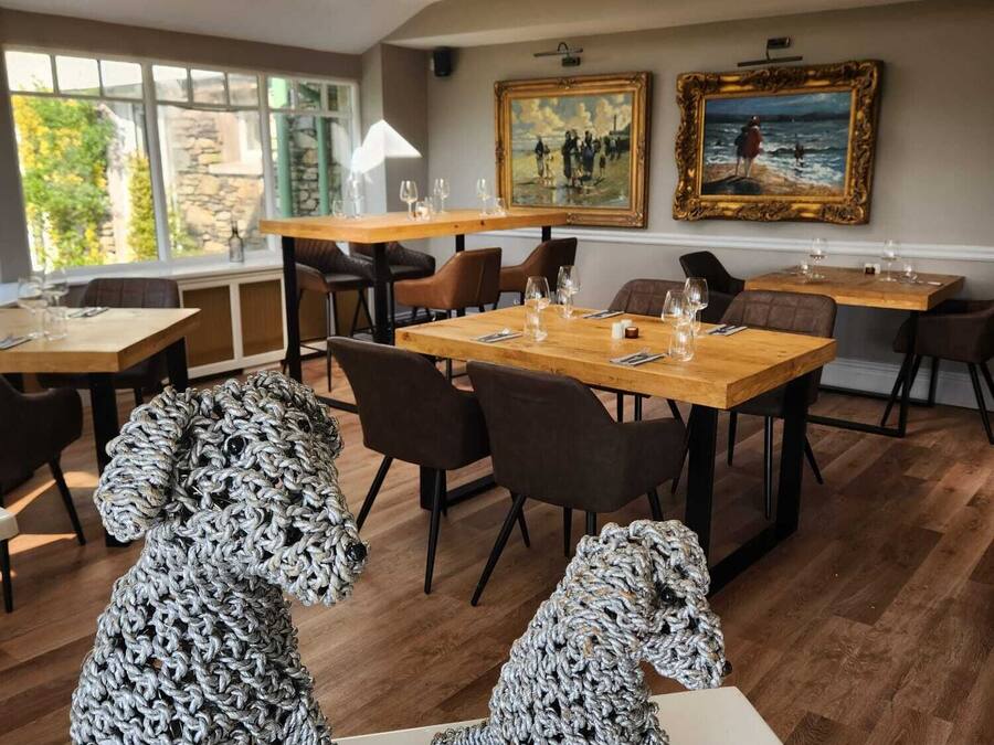 A dining area with tables, chairs, and two large knitted dog sculptures.