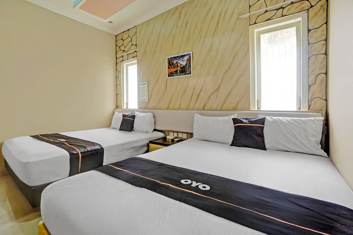 A hotel room with two beds, each with a black and white bedspread, a stone wall, a framed picture, and a window.