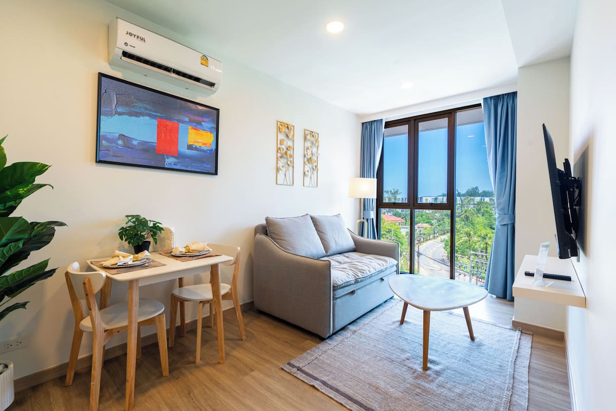 Una sala de estar moderna con un sofá, una mesa de comedor, sillas y un televisor.
