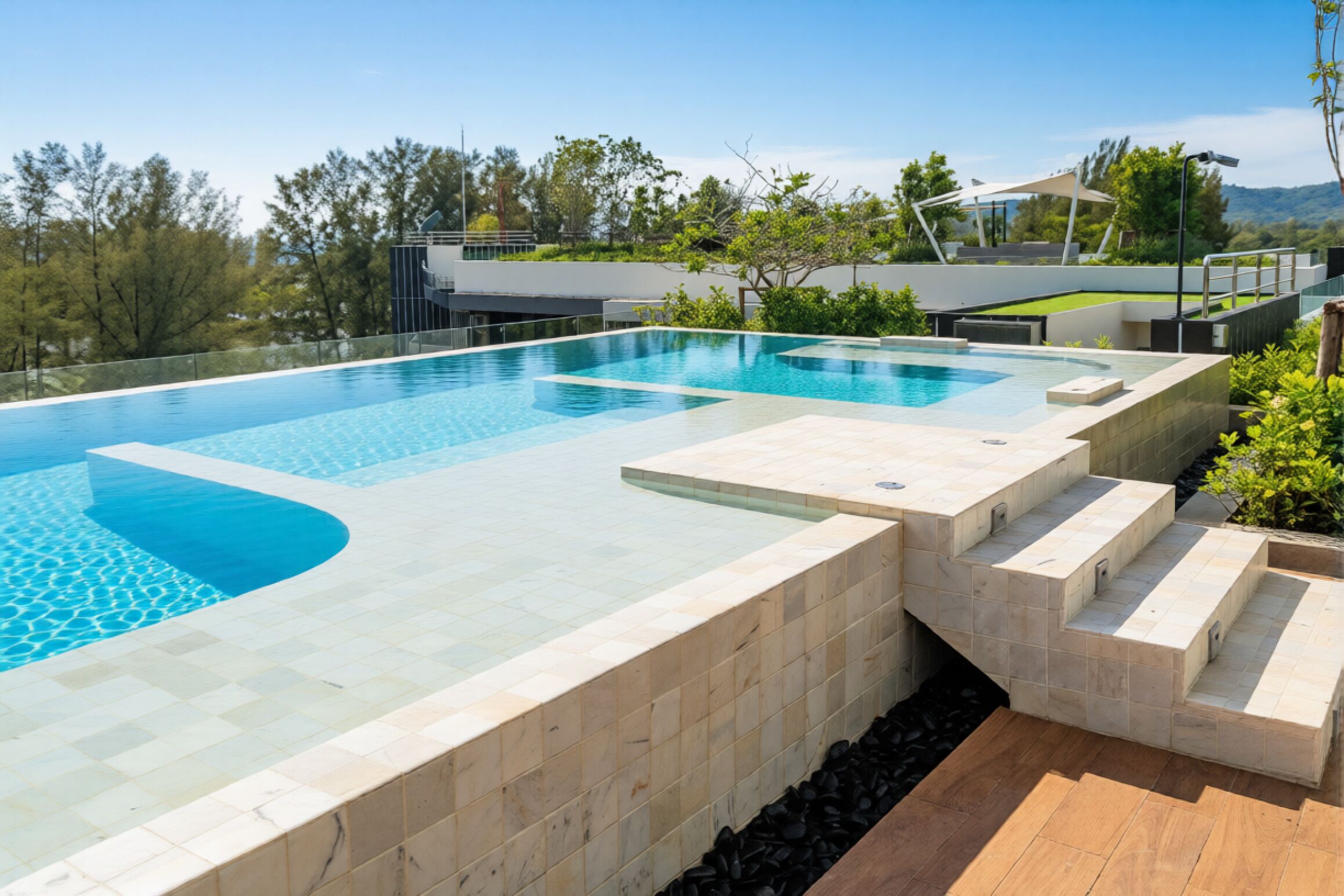 Una piscina moderna al aire libre con agua azul cristalina, rodeada por una terraza de piedra y escalones que bajan al agua.