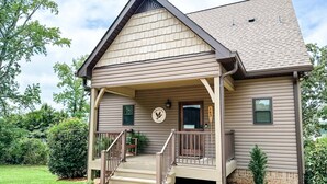 A two-story house with a covered porch, a front door, and a small window. - Mallards Nest on Lay Lake: Game Room & Boat Ramp (Shelby)