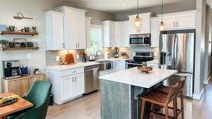 A modern kitchen with white cabinets, stainless steel appliances, and a central island. - Mallards Nest on Lay Lake: Game Room & Boat Ramp (Shelby)
