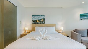 Habitación de hotel con cama, dos mesitas de noche, lámpara, un cuadro y una silla.