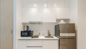 Una cocina moderna con armarios blancos, un refrigerador de acero inoxidable, un microondas y una cafetera.