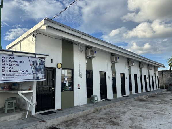 A building with a signboard listing amenities like Wifi, spring bed, lemari, and ac.