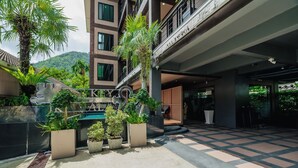 A hotel courtyard with potted plants, a pool, and a checkered floor. - Westkey Kamala Hotel (Kamala)