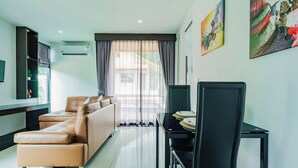 A modern living room with a sofa, dining table, chairs, and artwork on the walls. - Westkey Kamala Hotel (Kamala)