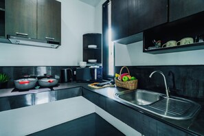 Una cocina moderna con un lavamanos de acero inoxidable, un microondas y una estufa. Hay una cesta de fruta sobre la encimera.