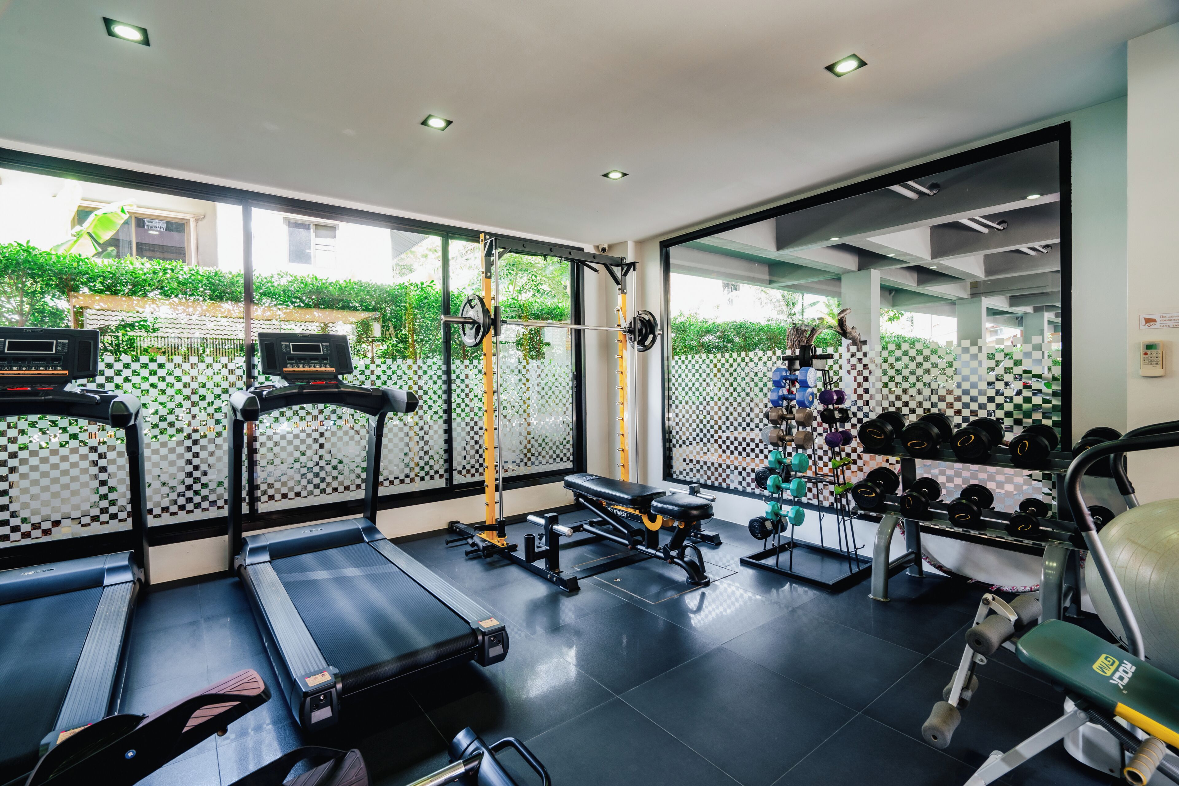 Academia com esteiras, bancos de musculação, halteres e bolas de exercício.