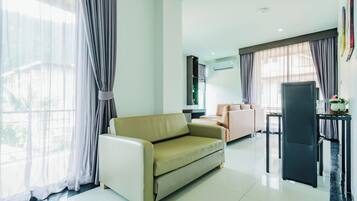 A modern living room with a sofa, a TV, a dining area, and a large window with curtains.