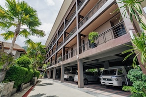 A multi-story parking structure with vehicles parked underneath, surrounded by greenery and a clear sky. - Westkey Kamala Hotel (Kamala)