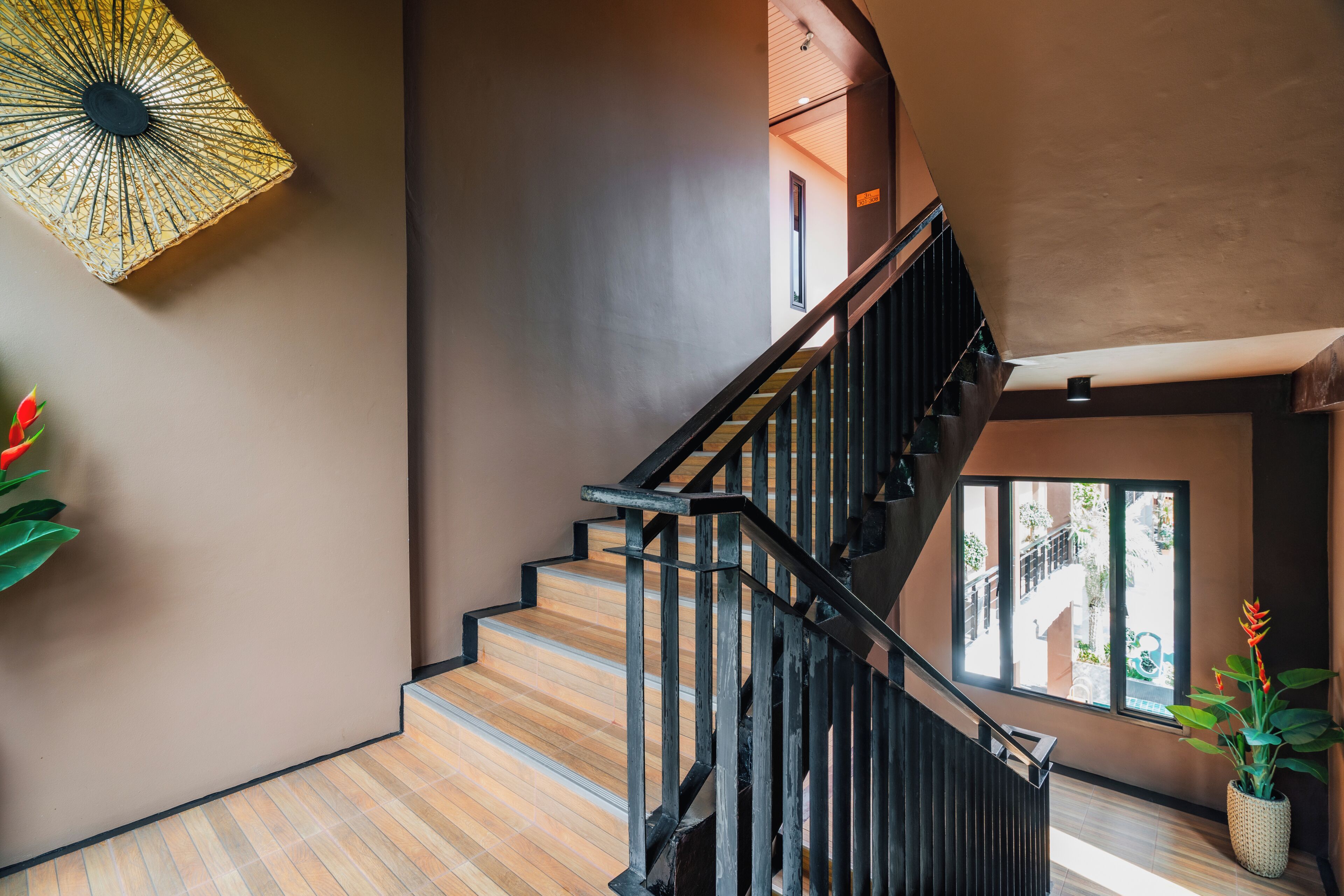 A staircase with wooden steps and black railings, leading to a landing with a large window.