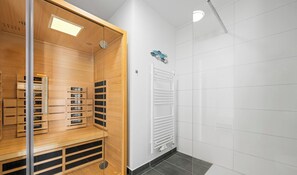 A modern bathroom with a wooden vanity, a white radiator, and a tiled floor.