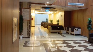 A hotel lobby with a checkered floor, seating area, reception desk, and a signboard. - Olyaan Silver (Makkah)