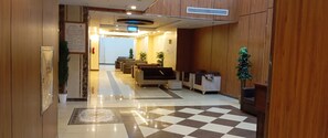 A hotel lobby with a checkered floor, seating area, reception desk, and a signboard. - Olyaan Silver  (Makkah)