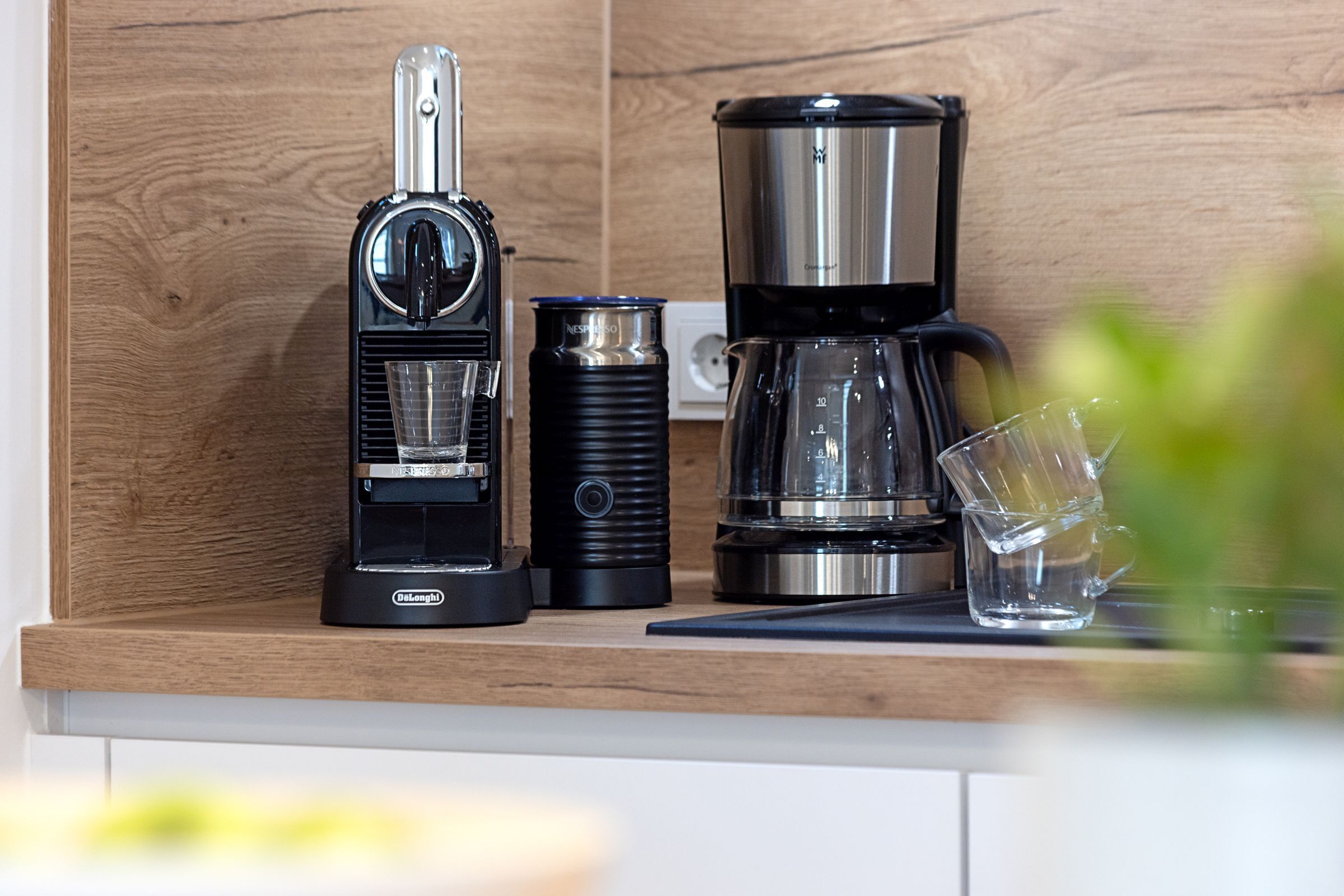 A kitchen counter with a coffee maker, a kettle, and a glass pitcher.