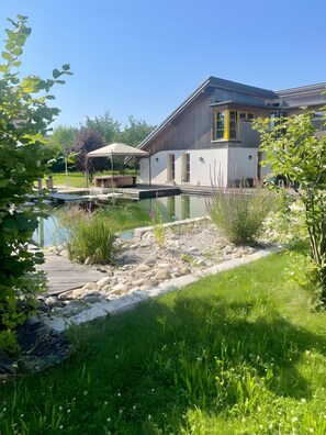 A modern building with a pool, surrounded by greenery and a stone pathway. - Holiday Home with Shared Pool, Terrace and Wi-Fi (Gengenbach)
