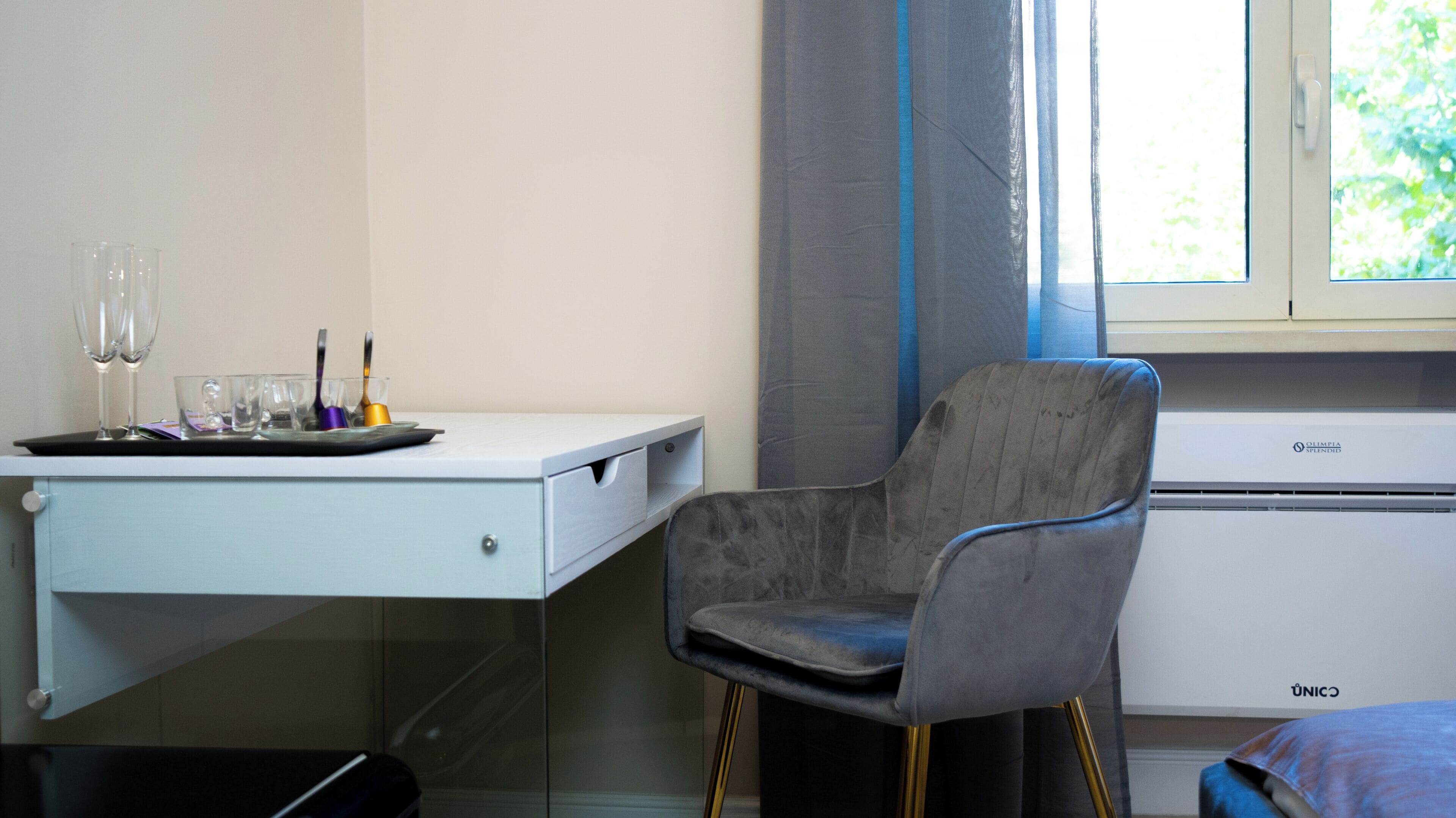 Ein Zimmer mit Schreibtisch, Stuhl und einem Vorhangfenster.