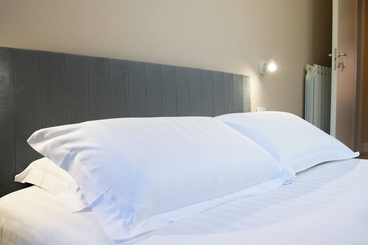Una cama bien hecha con sábanas blancas en una habitación de hotel.