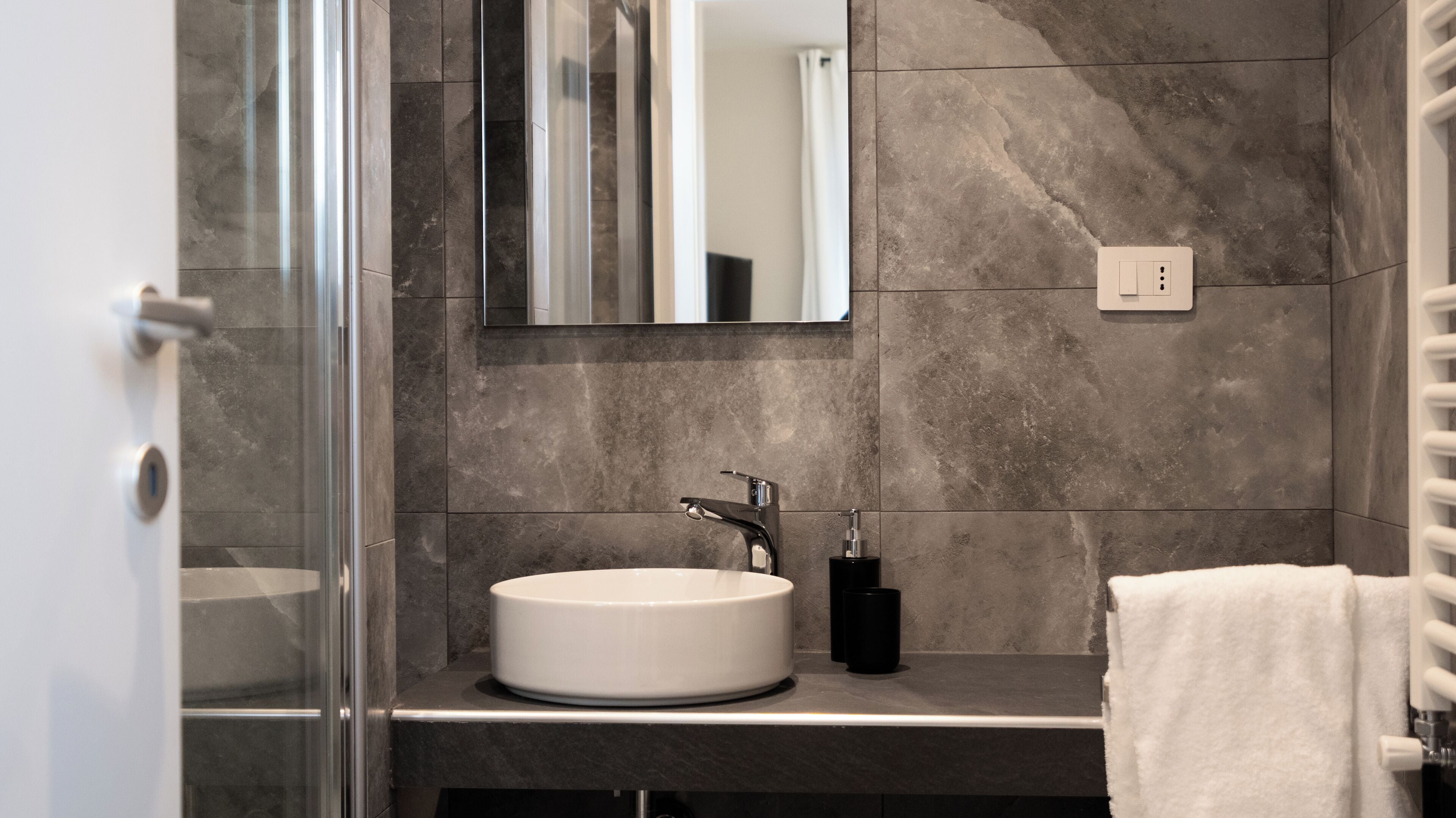 A modern bathroom with a white sink, a mirror, and a towel rack.