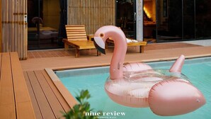 Ein modernes Gebäude mit großen Fenstern und einem Poolbereich mit einem Flamingo-Schwimmpunkt.
