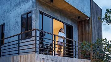Un moderno edificio de dos pisos con un balcón, ventanas grandes y luces colgantes.