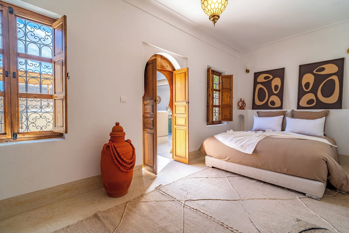 A bedroom with a bed, a large vase, and a rug.