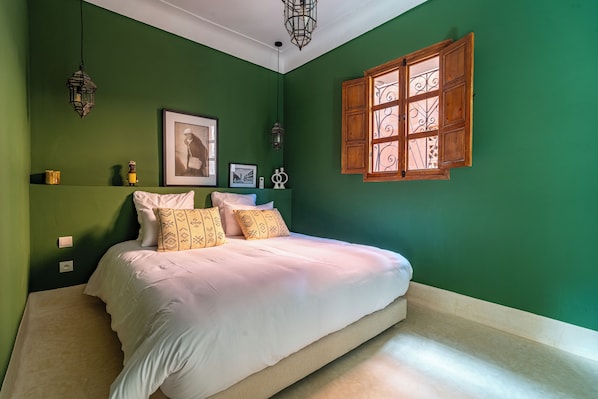 A bedroom with a bed, green walls, a window with decorative shutters, and two wall-mounted lanterns. - Riad Sofia Marrakech (Marrakech)
