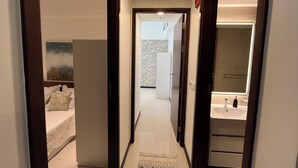 A narrow hallway leading to a bedroom with a bed and a large wardrobe. - 2-bedroom apartment with AC, fitness room and pool in the heartof  Colombo (Colombo)