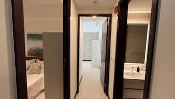 A narrow hallway leading to a bedroom with a bed and a large wardrobe.