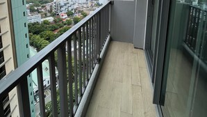 A balcony with a view of a cityscape, a glass door, and a wooden floor. - 2-bedroom apartment with AC, fitness room and pool in the heartof  Colombo (Colombo)