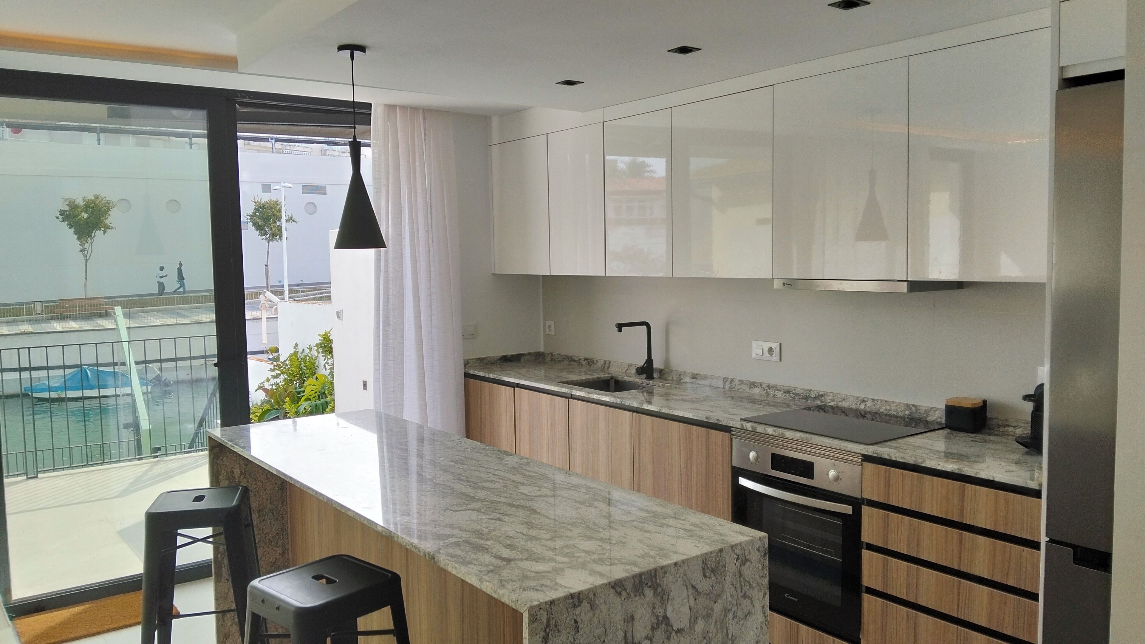 Una cocina moderna con encimera de mármol, armarios de madera, un grifo negro y un horno.