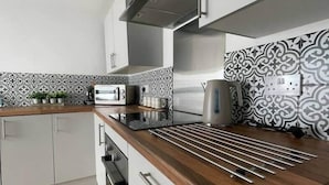Cozinha moderna com bancada de madeira, eletrodomésticos de aço inoxidável e painel de parede com padrão.