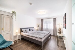 A modern bedroom with a bed, bedside tables, a chair, and a glass table.