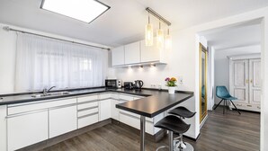 A modern kitchen with a central island, stainless steel appliances, and pendant lighting. - The Old Tailoring Shop (Balingen)