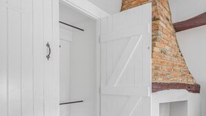 A room with a white wardrobe, a wooden floor, and a brick chimney. - Dolphin Cottage, Oxfordshire, England (Oxfordshire)