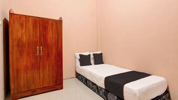 A bedroom with a wooden wardrobe, a bed with black and white bedding, and a patterned bed skirt.