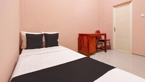 Een slaapkamer met een bed, een houten bureau en een gesloten deur.