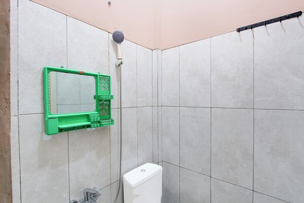 A bathroom with a toilet, a green-framed mirror, and a shower head. - Hotel O Guesthouse Alun Alun Purwokerto (Sukaradja)