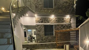 Une piscine bordée d’un mur en pierre et dotée d’un escalier menant à un niveau supérieur.