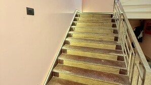 A staircase with glass railings and a handrail, leading to a landing with a light fixture.