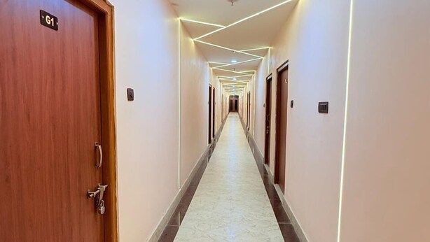 A long, narrow hallway with a marble floor, wooden doors, and modern lighting fixtures.