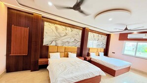 A modern bedroom with two beds, wooden paneling, a ceiling fan, and a large window.
