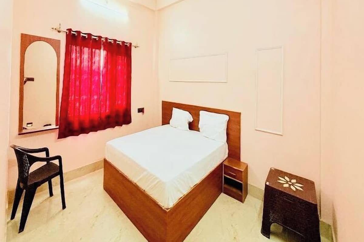 Quarto com cama, cadeira, mesa de cabeceira, mesa pequena, ventoinha no teto e espelho.