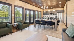 A modern kitchen with a dining area, large windows, and a wooden ceiling. - New Modern 4BR Mtn Home w/ Indoor Pool, Rooftop Patio, Game Room, & Hot Tub (Pigeon Forge)