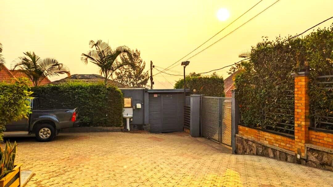 A paved driveway leading to a gated entrance with a vehicle parked nearby.